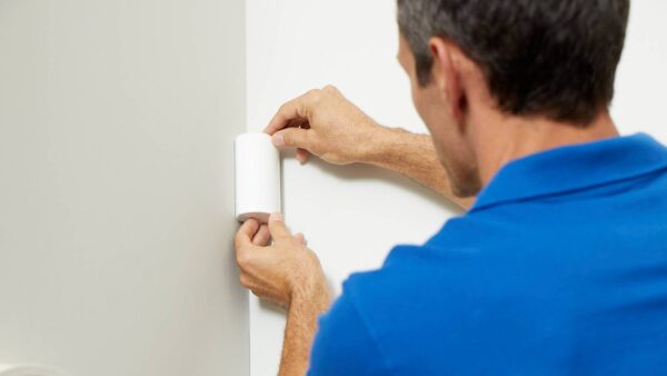 Technician installing a motion detector in a home.